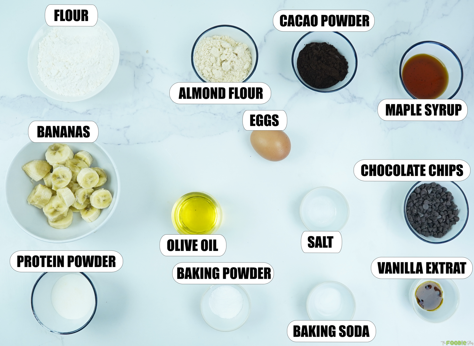 Ingredients for Double Chocolate Protein Muffins including bananas, flour, almond flour, cacao powder, protein powder, maple syrup, olive oil, egg, vanilla, baking powder, baking soda, salt, and chocolate chips.