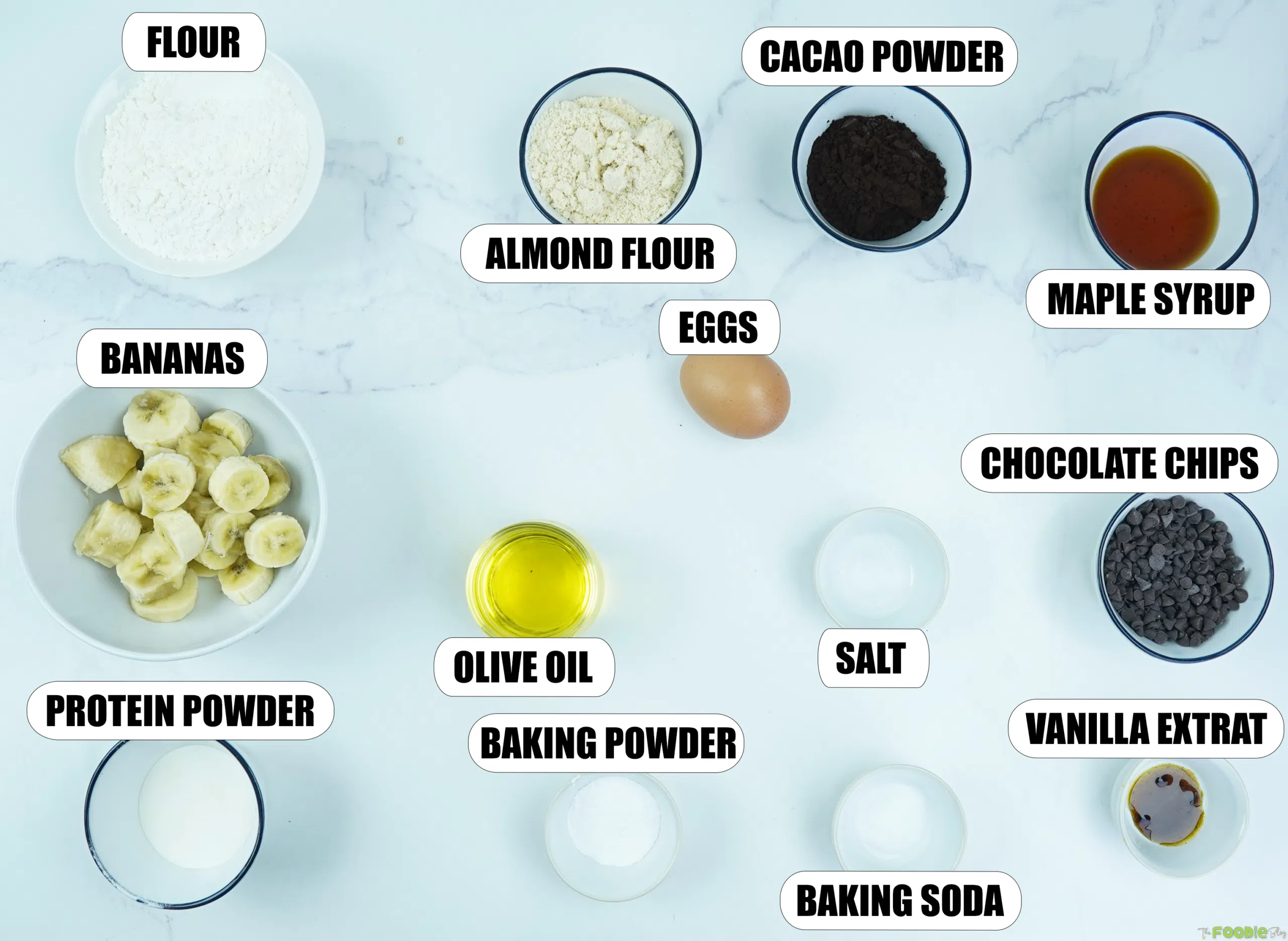 Ingredients for Double Chocolate Protein Muffins including bananas, flour, almond flour, cacao powder, protein powder, maple syrup, olive oil, egg, vanilla, baking powder, baking soda, salt, and chocolate chips.