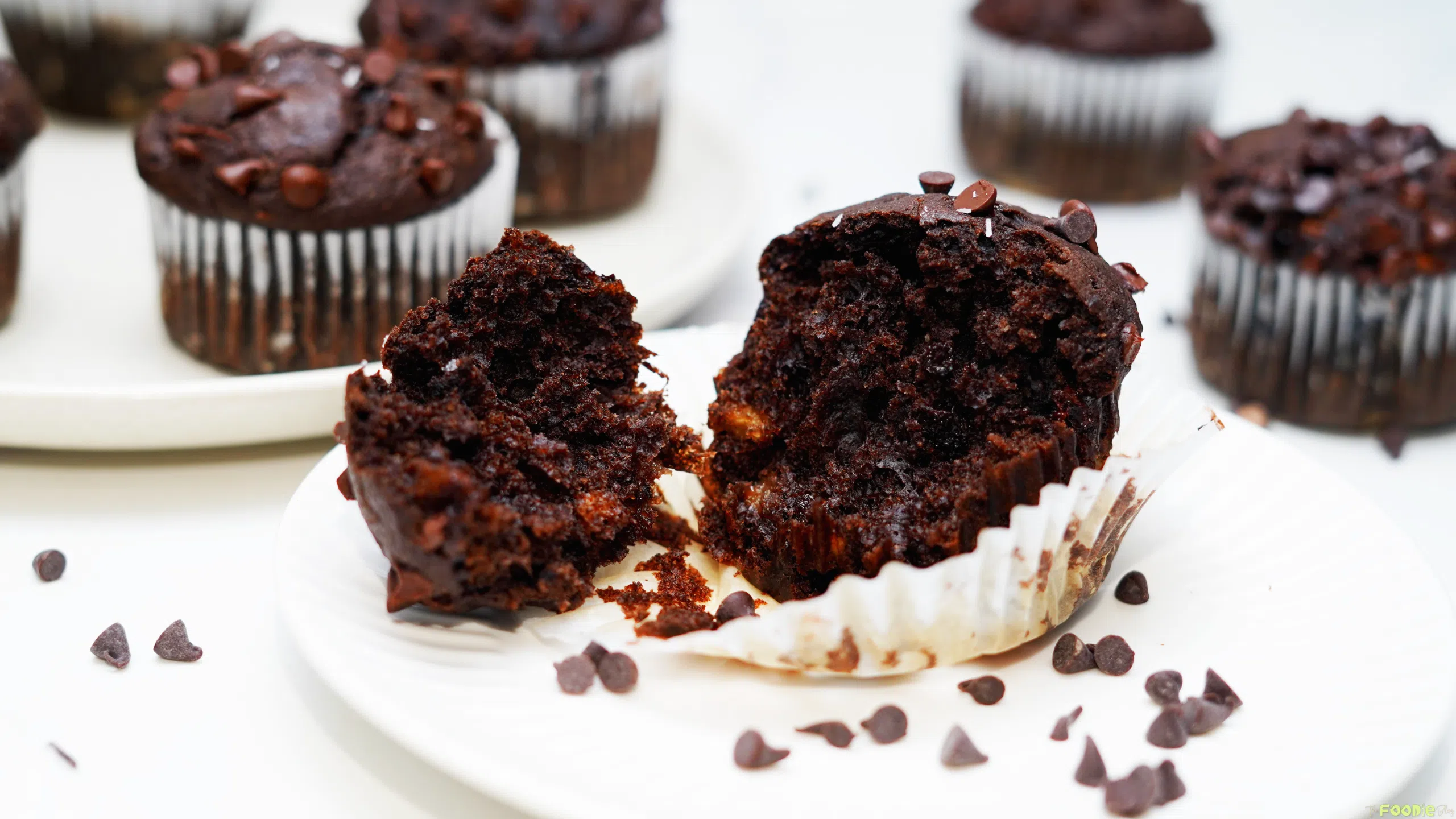 Split double chocolate protein muffin showing a moist chocolate crumb with chocolate chips inside.