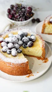 Easy Classic Baked Cheesecake topped with blueberries, cherries, and powdered sugar.
