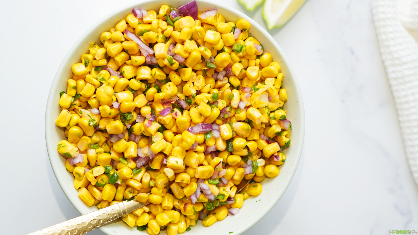 Fresh corn salsa with red onion, jalapeños, cilantro, and lime juice in a serving bowl.