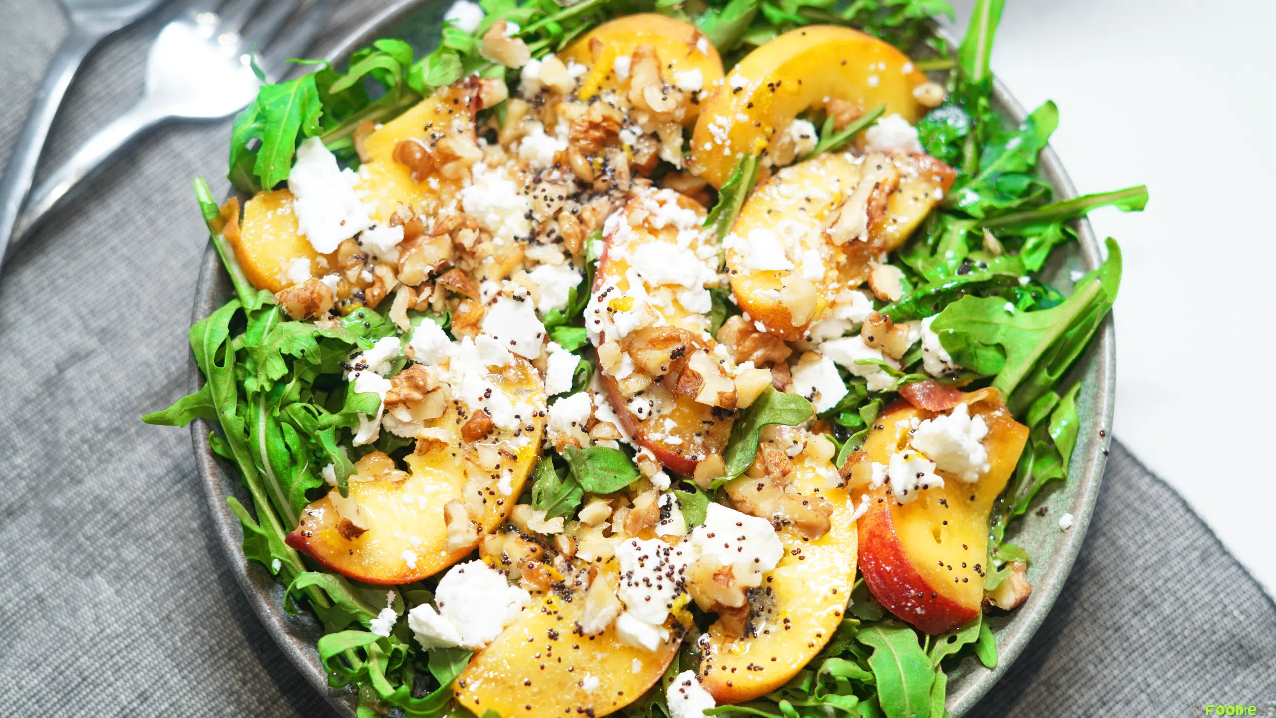 Close-up of peach salad with arugula, feta cheese, walnuts, and poppyseed dressing.