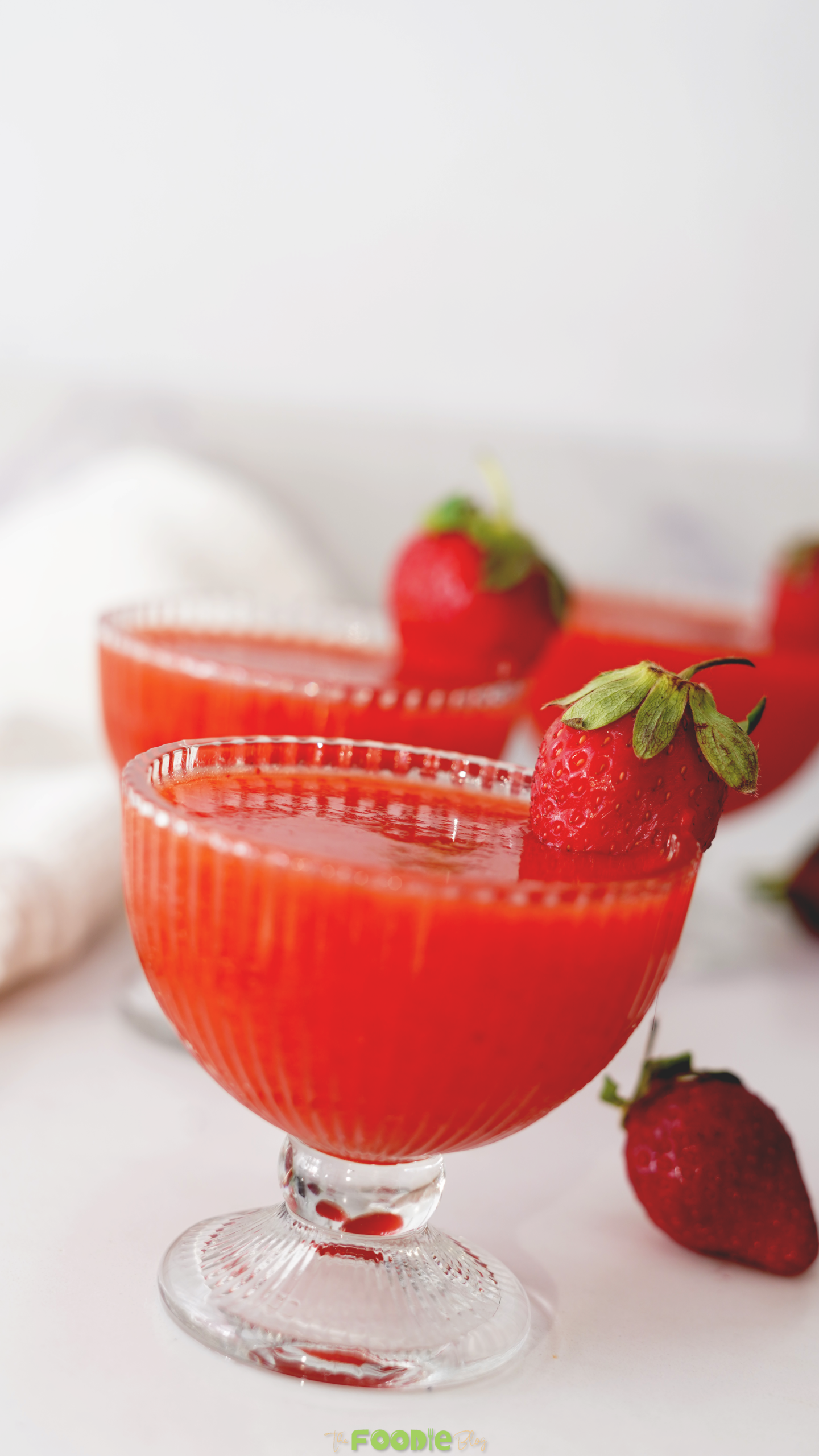 Frozen strawberry daiquiri served in glasses with fresh strawberries on the rim