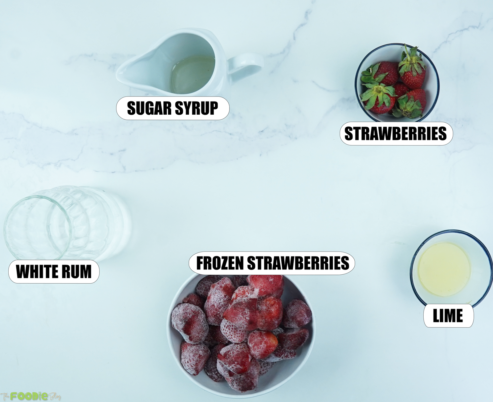 Ingredients for frozen strawberry daiquiri with strawberries, lime juice, white rum, and sugar syrup.