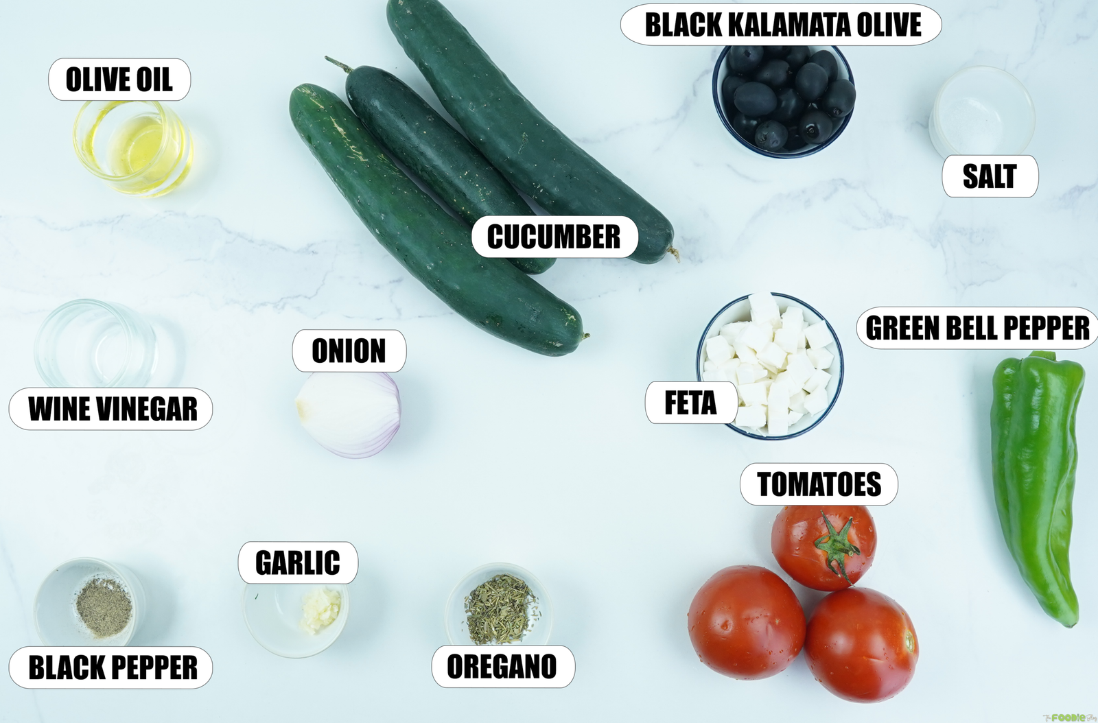 Ingredients for Greek Salad including cucumbers, tomatoes, green bell pepper, feta, Kalamata olives, onion, olive oil, red wine vinegar, garlic, oregano, salt, and black pepper.