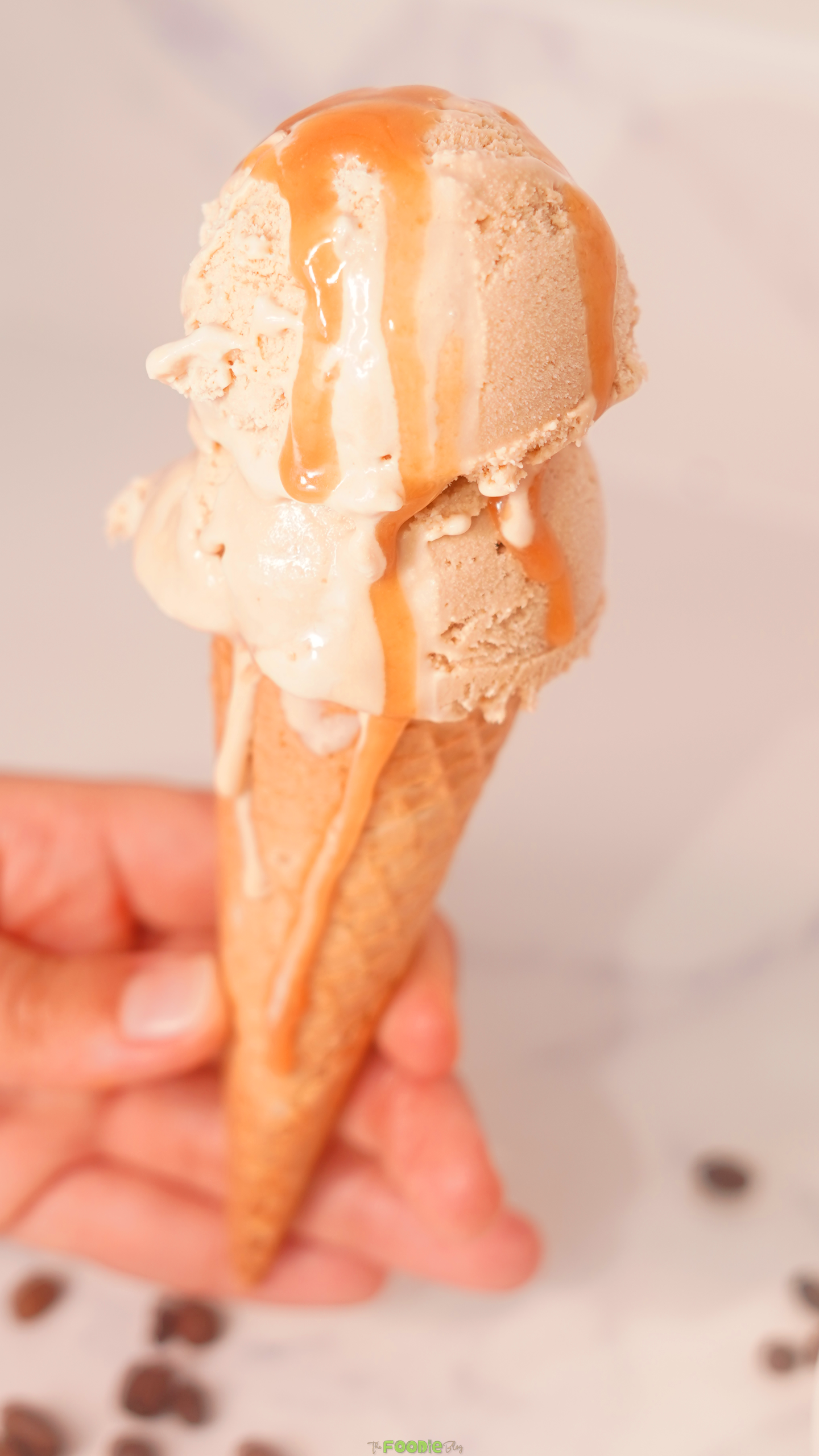 Coffee ice cream scoops in a waffle cone drizzled with caramel sauce