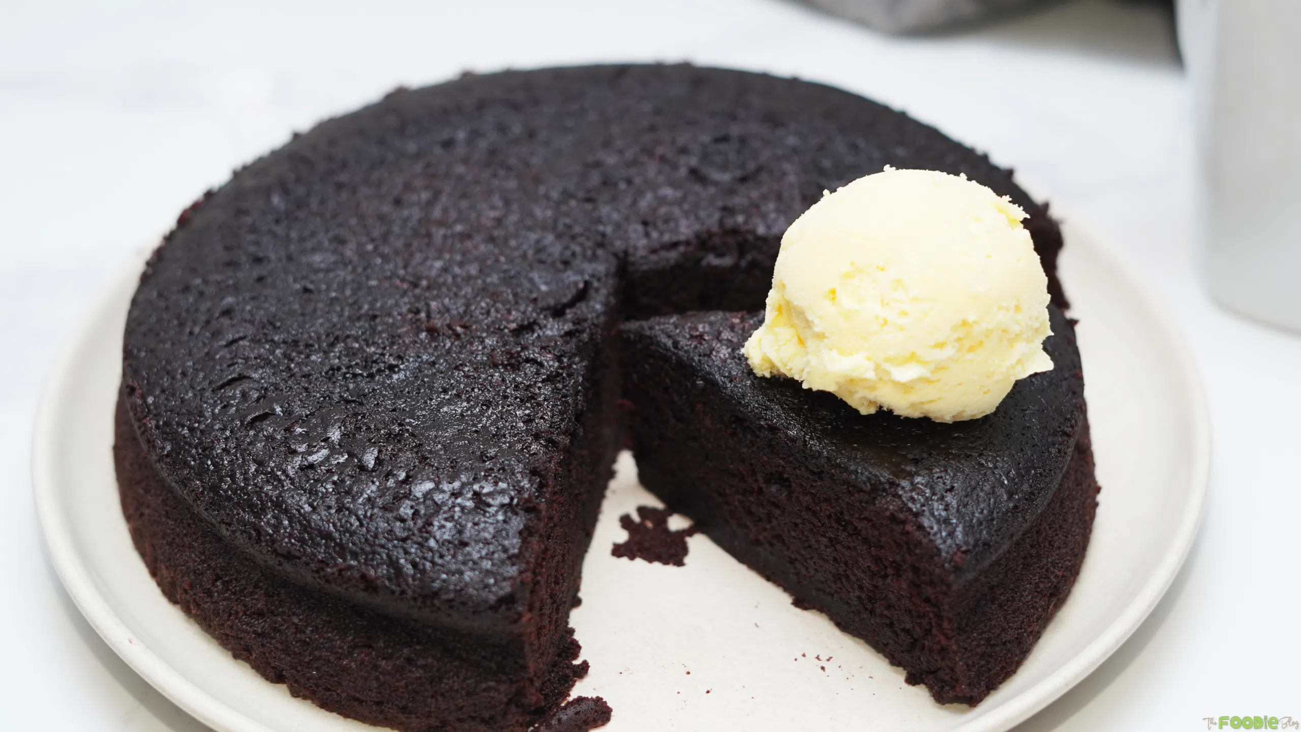 Hot chocolate fudge cake with a slice removed and vanilla ice cream on top.