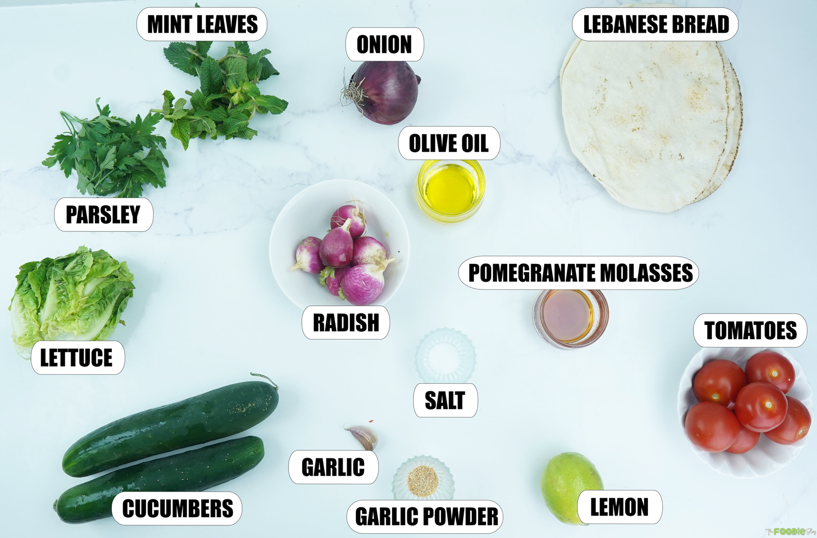 Ingredients for Lebanese Fattoush Salad including lettuce, cucumbers, tomatoes, radishes, mint, parsley, onion, Lebanese bread, olive oil, lemon, garlic, and pomegranate molasses.