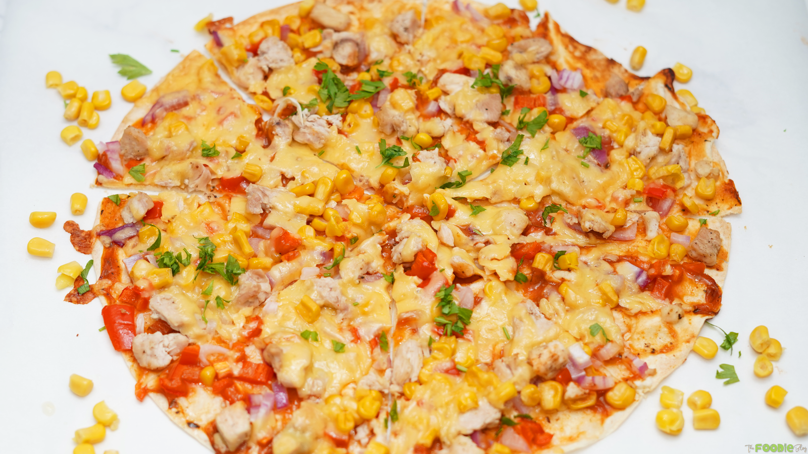 Mexican Pizzas made with flatbread, enchilada sauce, chicken, corn, red onion, bell pepper, and melted cheese.