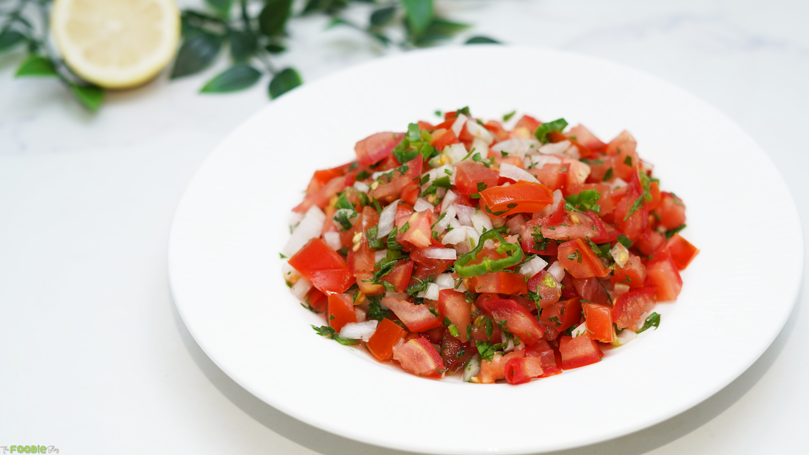 Pico de Gallo with diced tomatoes, white onion, cilantro, and jalapeño served on a white plate.