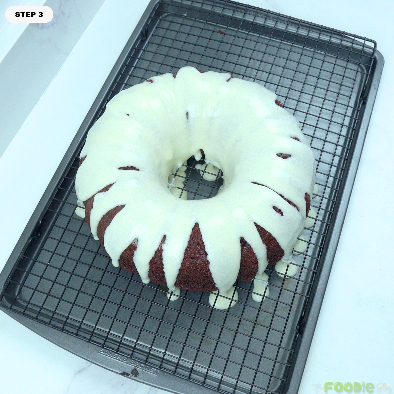 Cream cheese glaze poured over a cooled red velvet Bundt cake on a wire rack