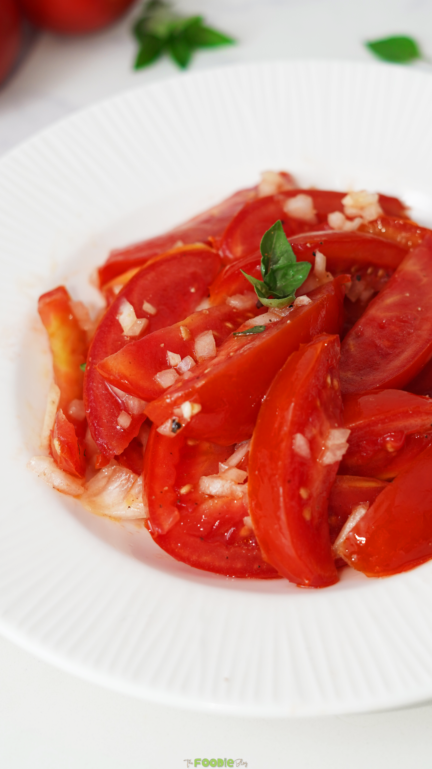 Close-up of tomato salad with fresh basil, minced garlic, and shallots.