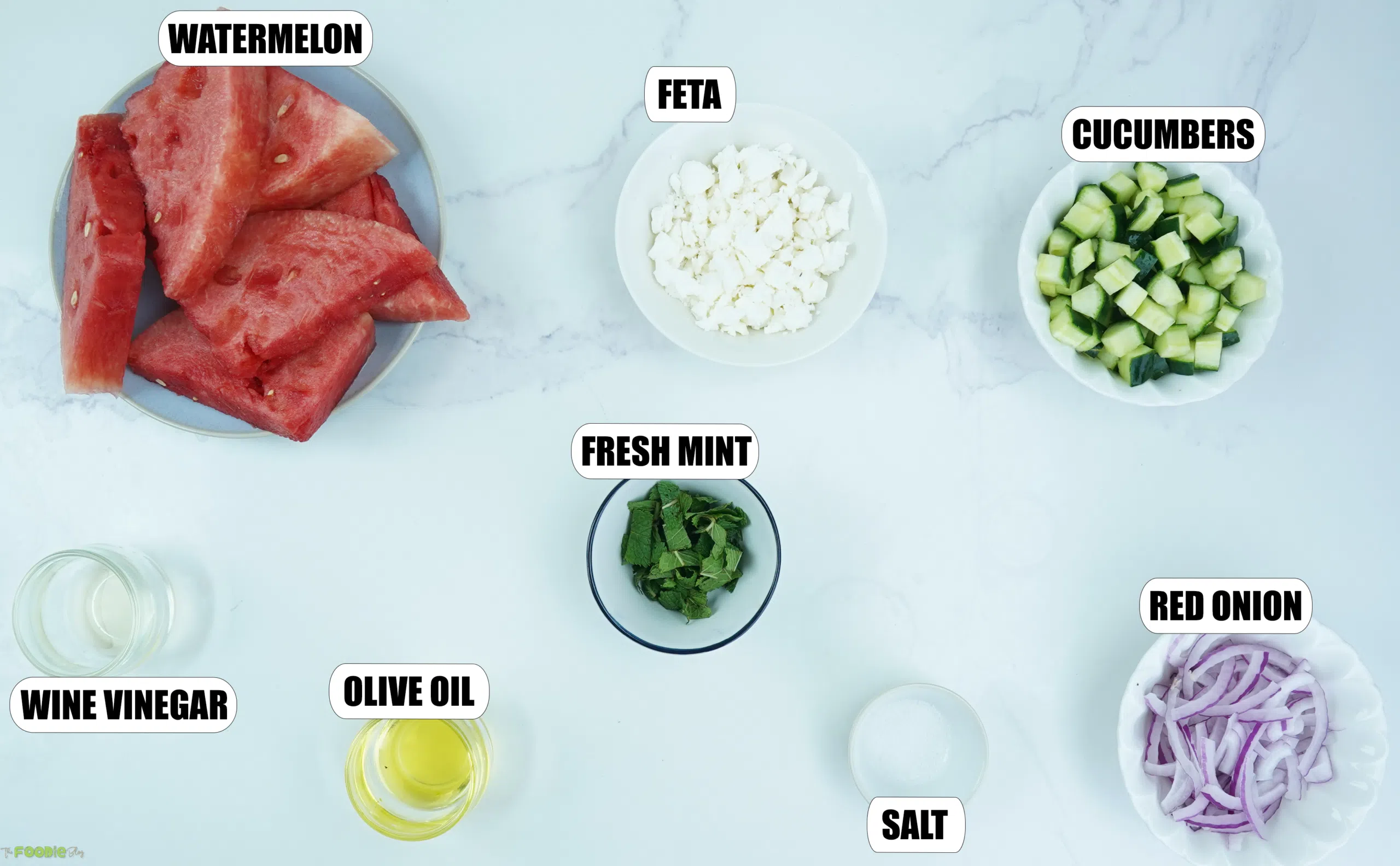 Ingredients for watermelon feta salad with watermelon, feta, cucumber, mint, red onion, olive oil, vinegar, and salt.
