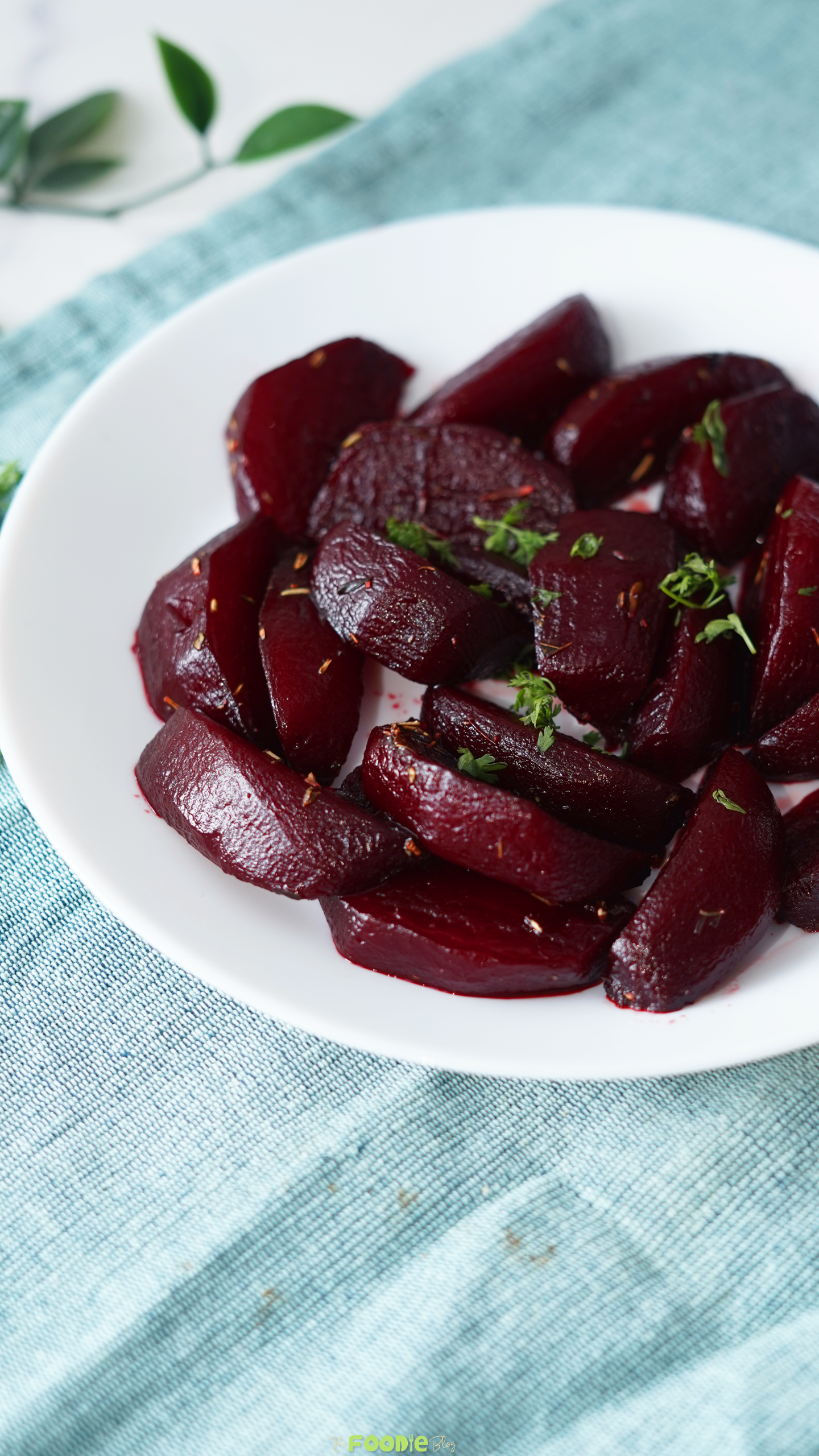 Close-up of balsamic glazed beets on a white plate with thyme leaves and a deep red glossy finish.