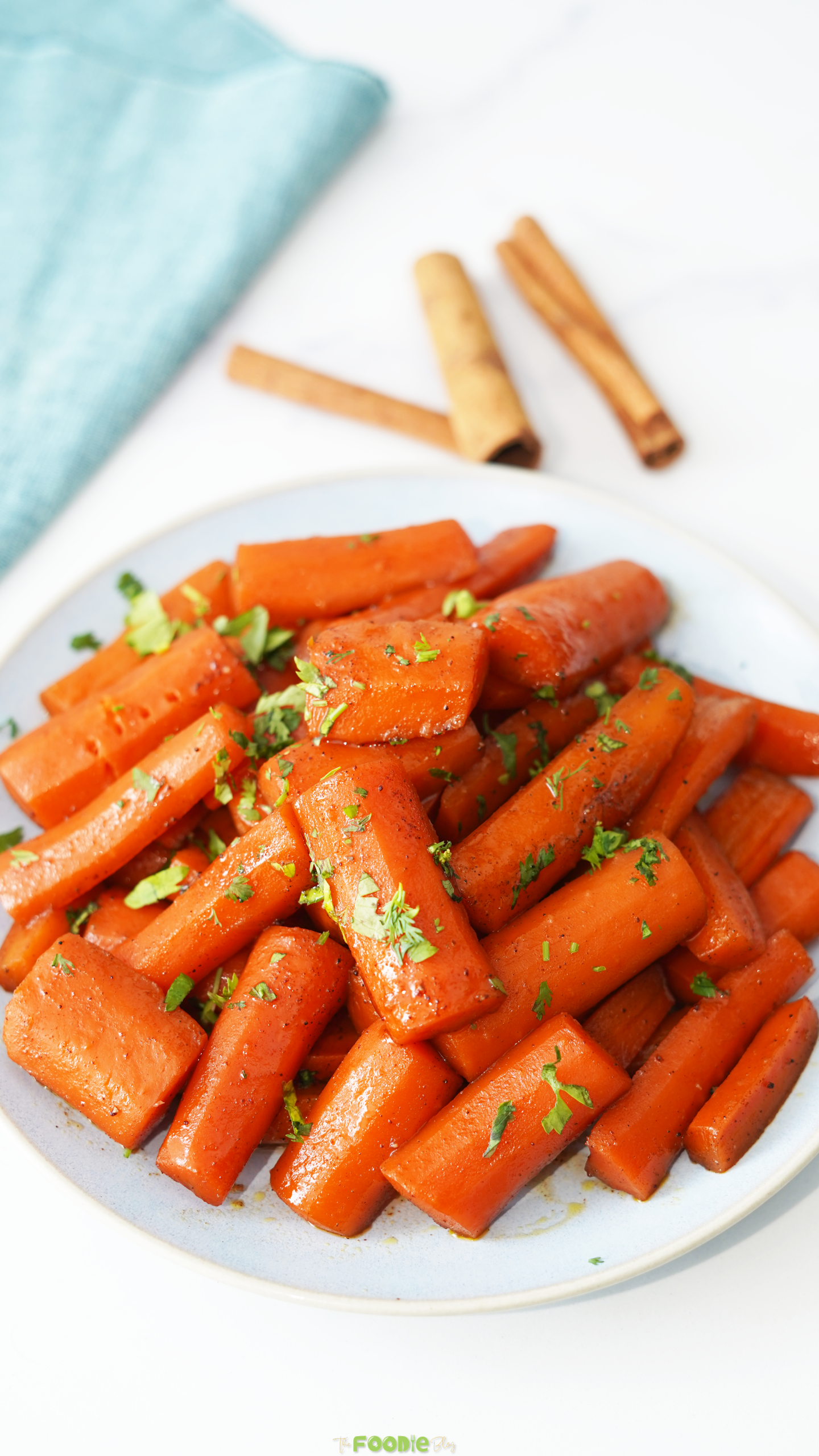 Brown sugar candied carrots served with parsley and cinnamon sticks in the background.