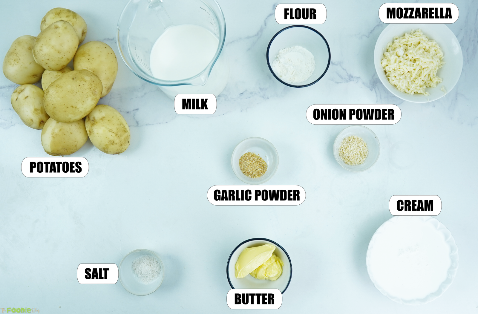 Ingredients for Cheesy Scalloped Potatoes with potatoes, milk, flour, mozzarella, cream, butter, garlic powder, onion powder, and salt.