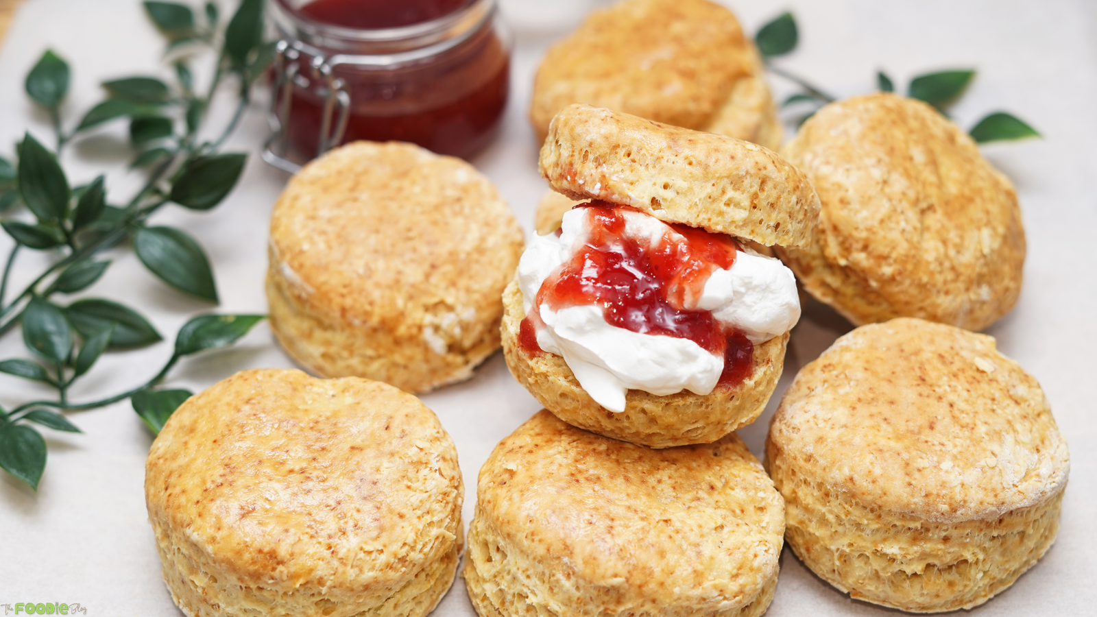 A tray of classic golden scones with strawberry jam and whipped cream