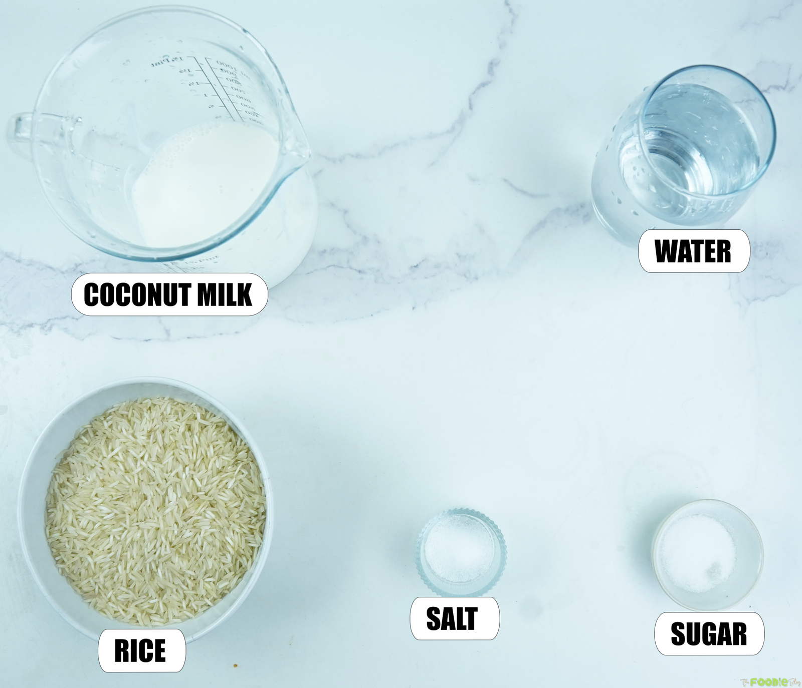 Ingredients for coconut rice including long-grain rice, coconut milk, water, salt, and sugar on a marble surface.