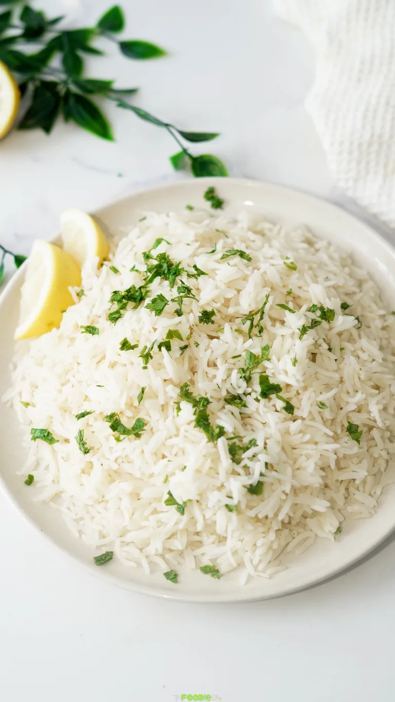 Fluffy coconut rice topped with fresh parsley and served with lemon wedges in a bowl.