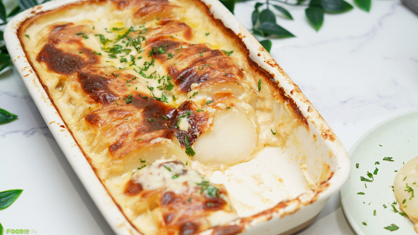 Creamy Cheesy Scalloped Potatoes in a baking dish with golden cheese and sliced potatoes.
