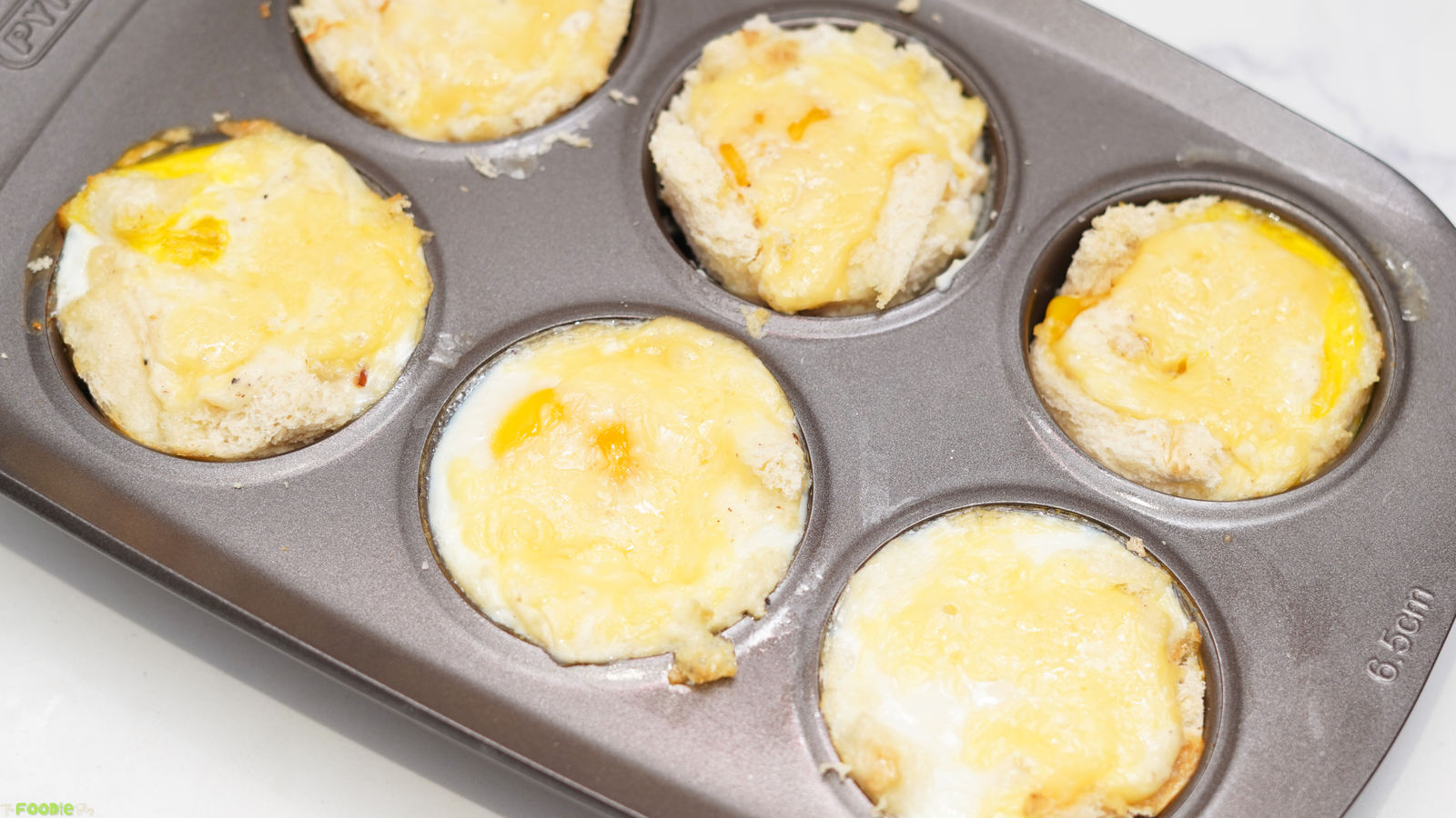Croque Madame Toastie Cups baked in a muffin tin with melted cheese and eggs.