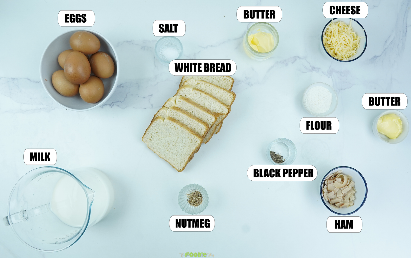 Ingredients for Croque Madame Toastie Cups with eggs, white bread, milk, butter, cheese, ham, flour, salt, black pepper, and nutmeg.