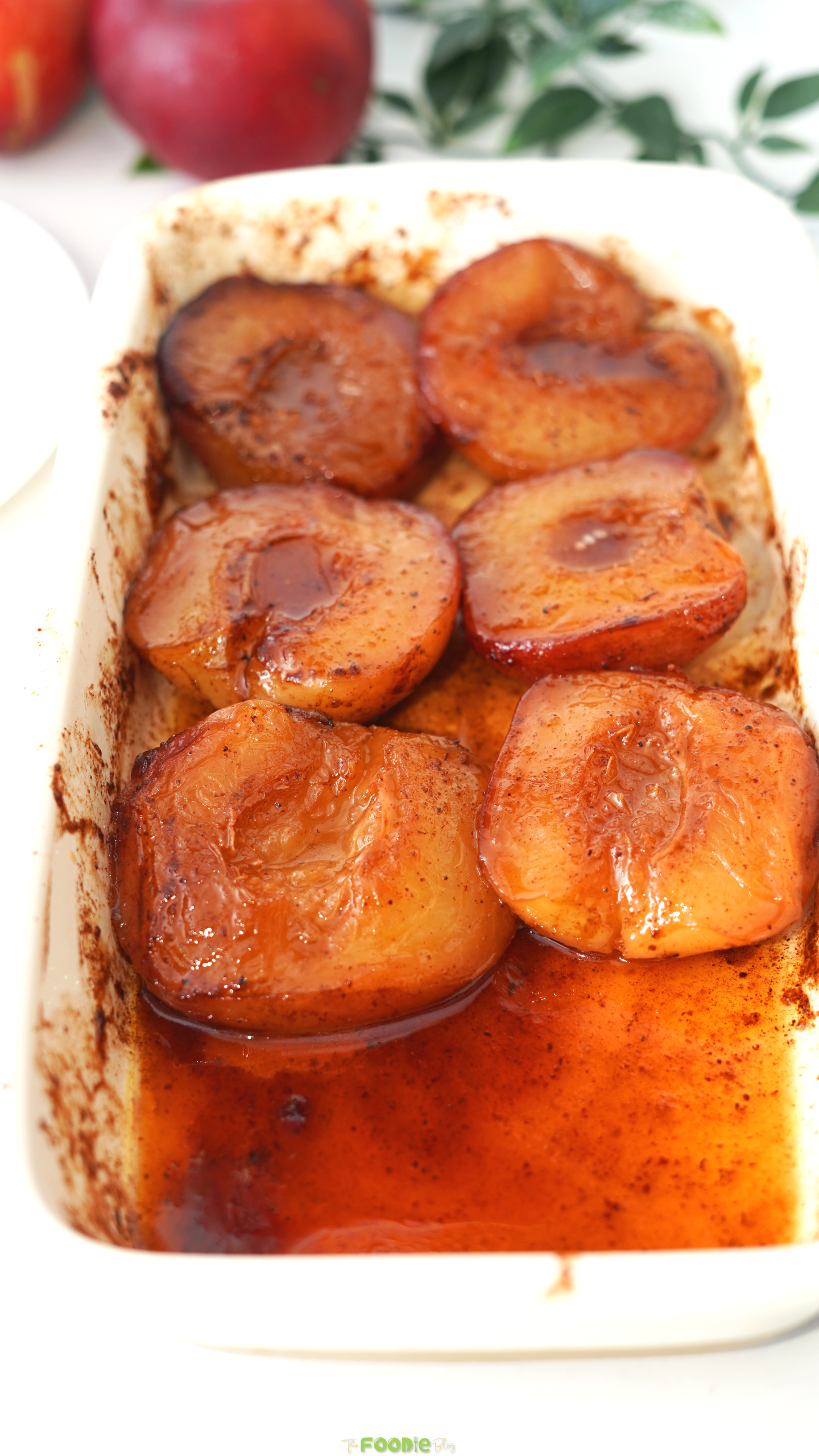 Tender baked peach halves sitting in warm honey and cinnamon sauce.