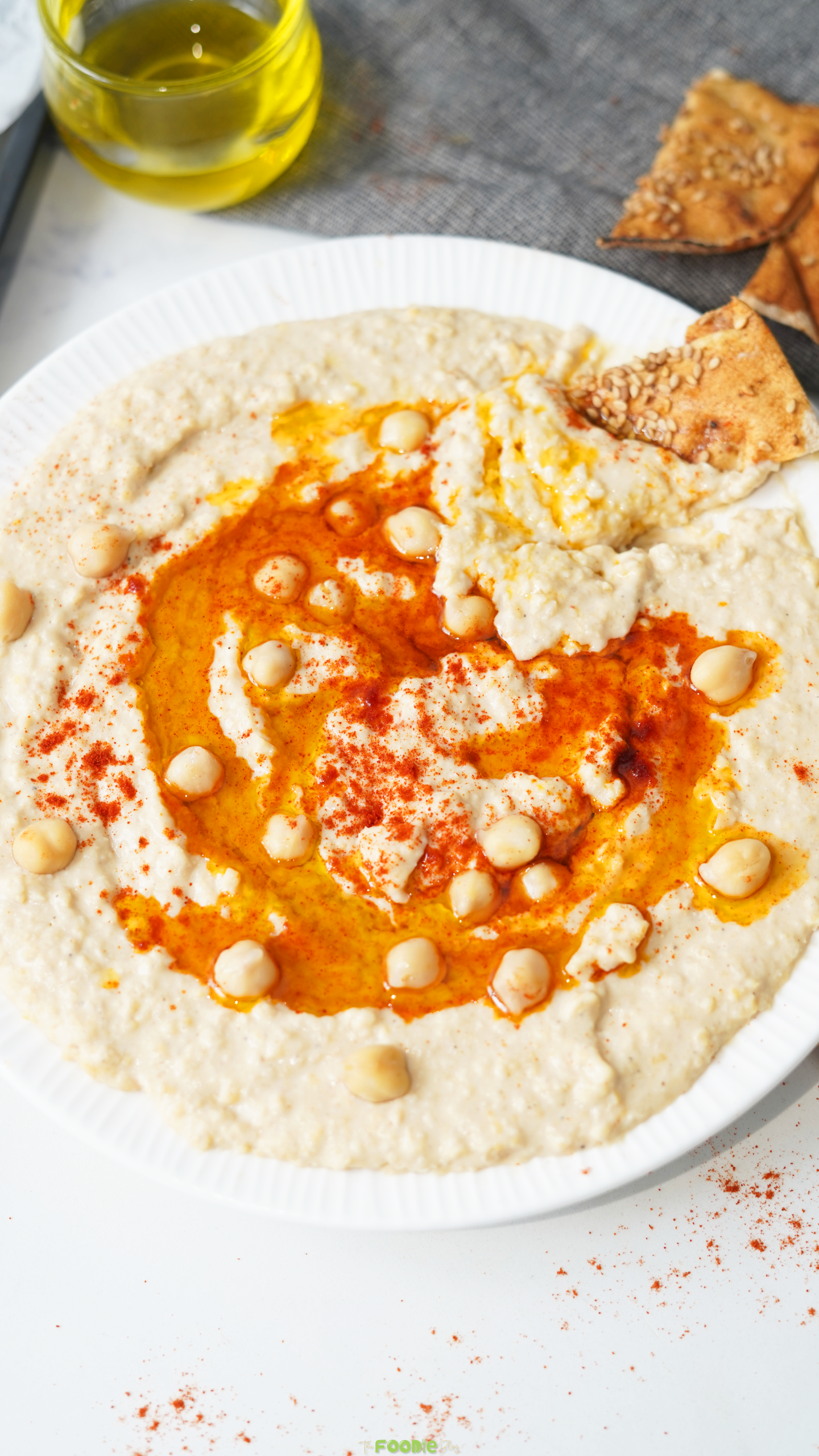 Creamy homemade hummus topped with chickpeas, paprika, and olive oil, served with crispy pita chips.