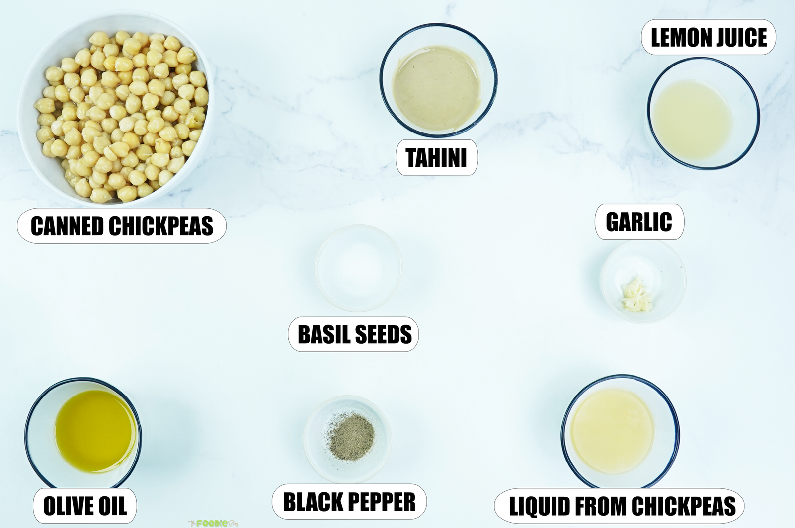 Overhead view of chickpeas, tahini, lemon juice, garlic, olive oil, salt, black pepper, and chickpea liquid for homemade hummus.