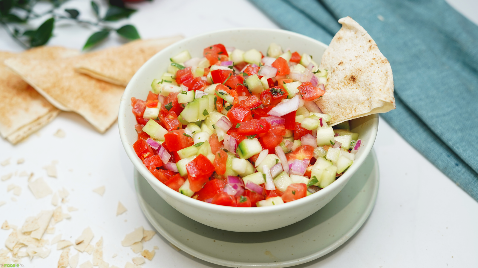 Easy tomato cucumber salad in a bowl with chopped tomatoes, cucumbers, red onion, herbs, and pita bread.