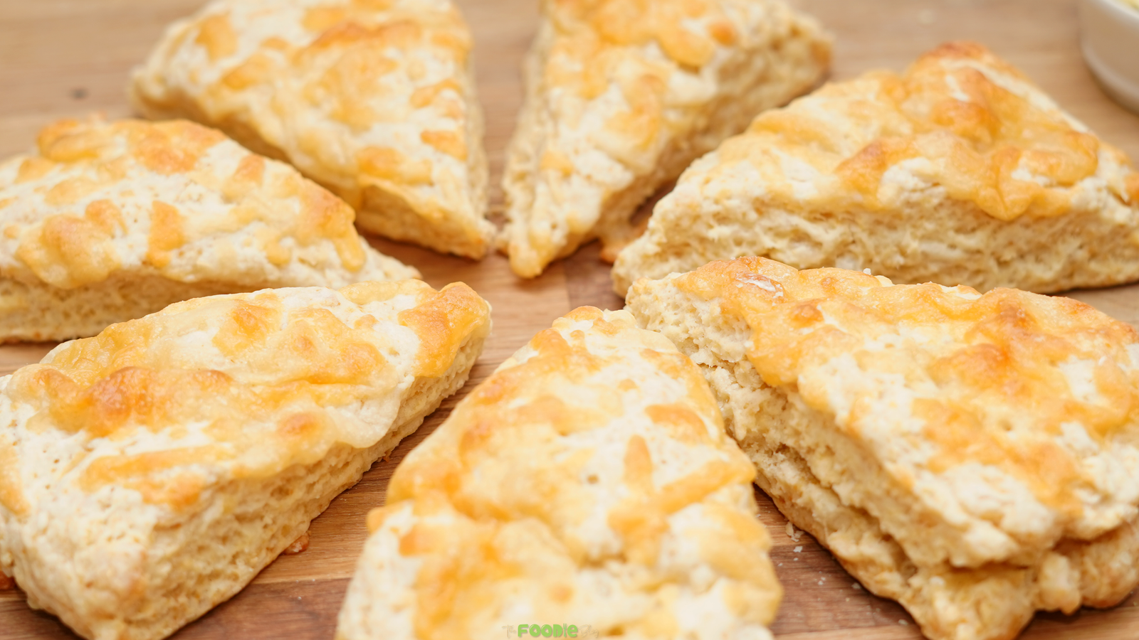 Golden baked Cheese Scones with melted cheese on top arranged on a wooden board.