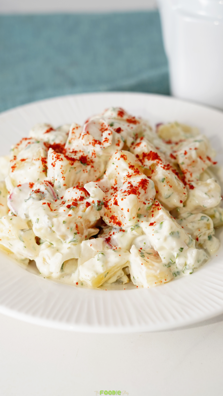 Close-up of homemade Potato Salad with creamy dressing, parsley, radishes, and paprika.