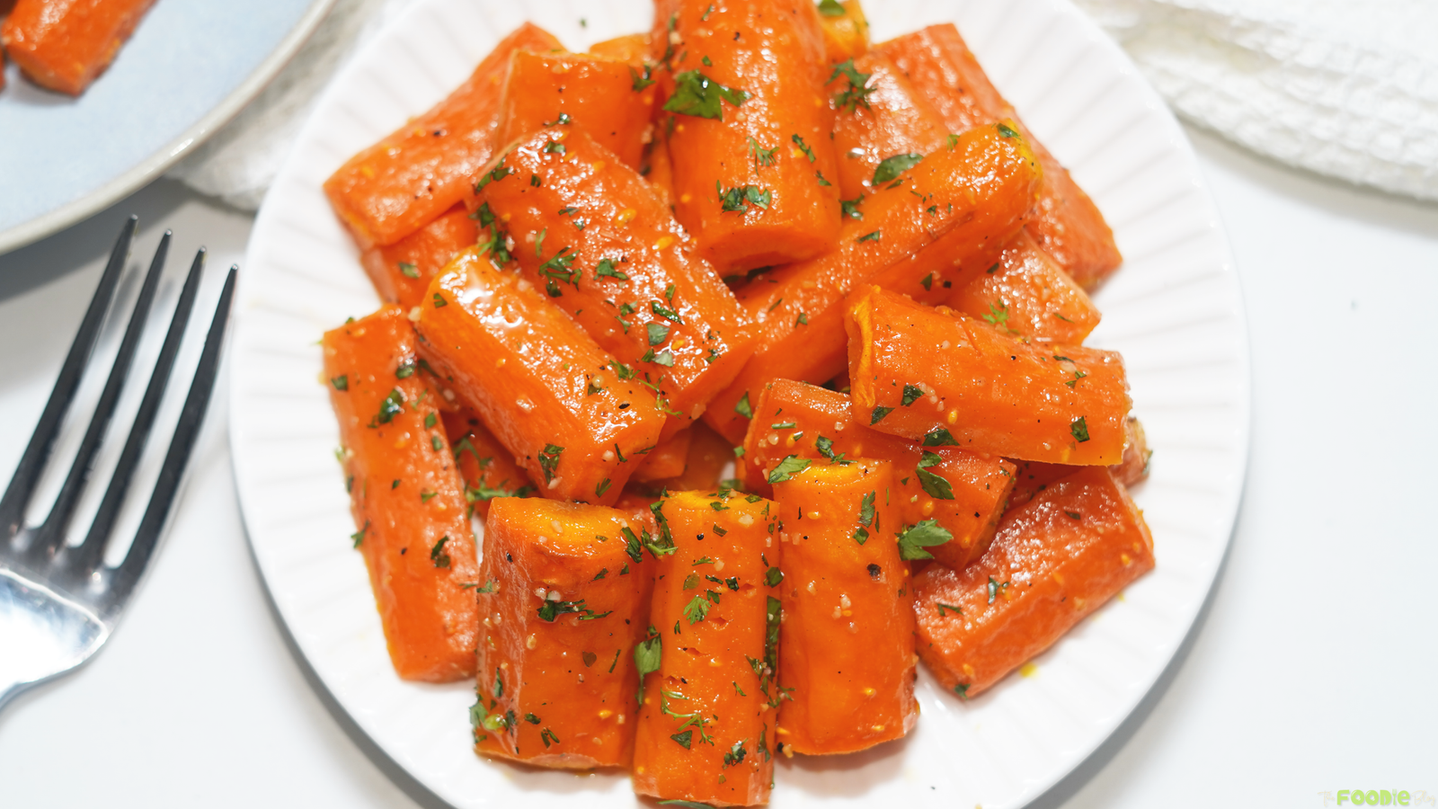 Close-up of Honey Roasted Carrots with herbs, black pepper, and a glossy honey glaze.