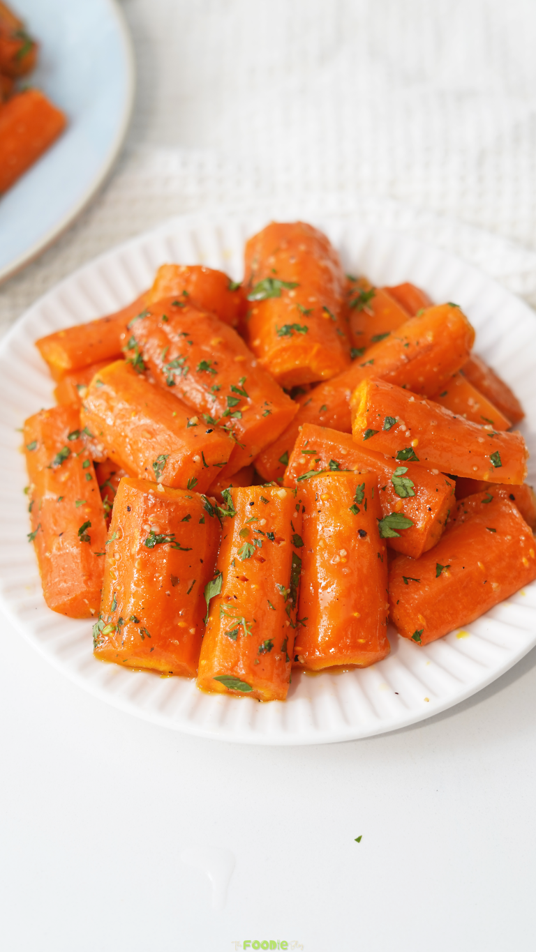 Honey Roasted Carrots served on a white plate with fresh herbs.