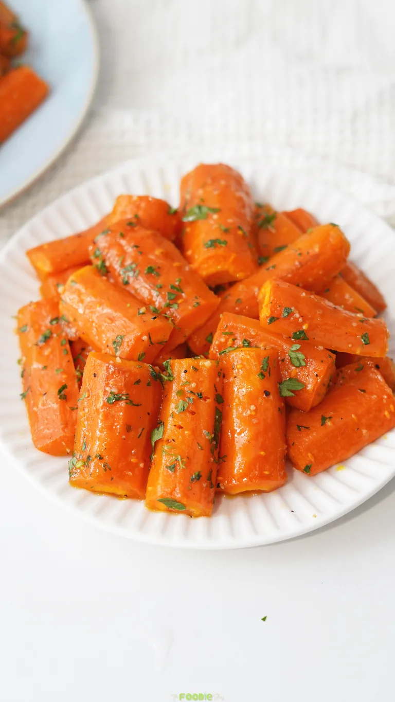 Honey Roasted Carrots served on a white plate with fresh herbs.