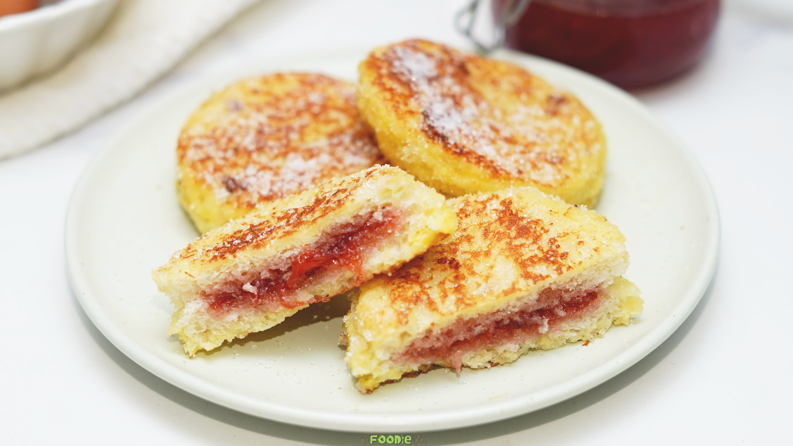 Golden sugar-coated jam jelly doughnut French toast cut open to show a warm strawberry jam filling.