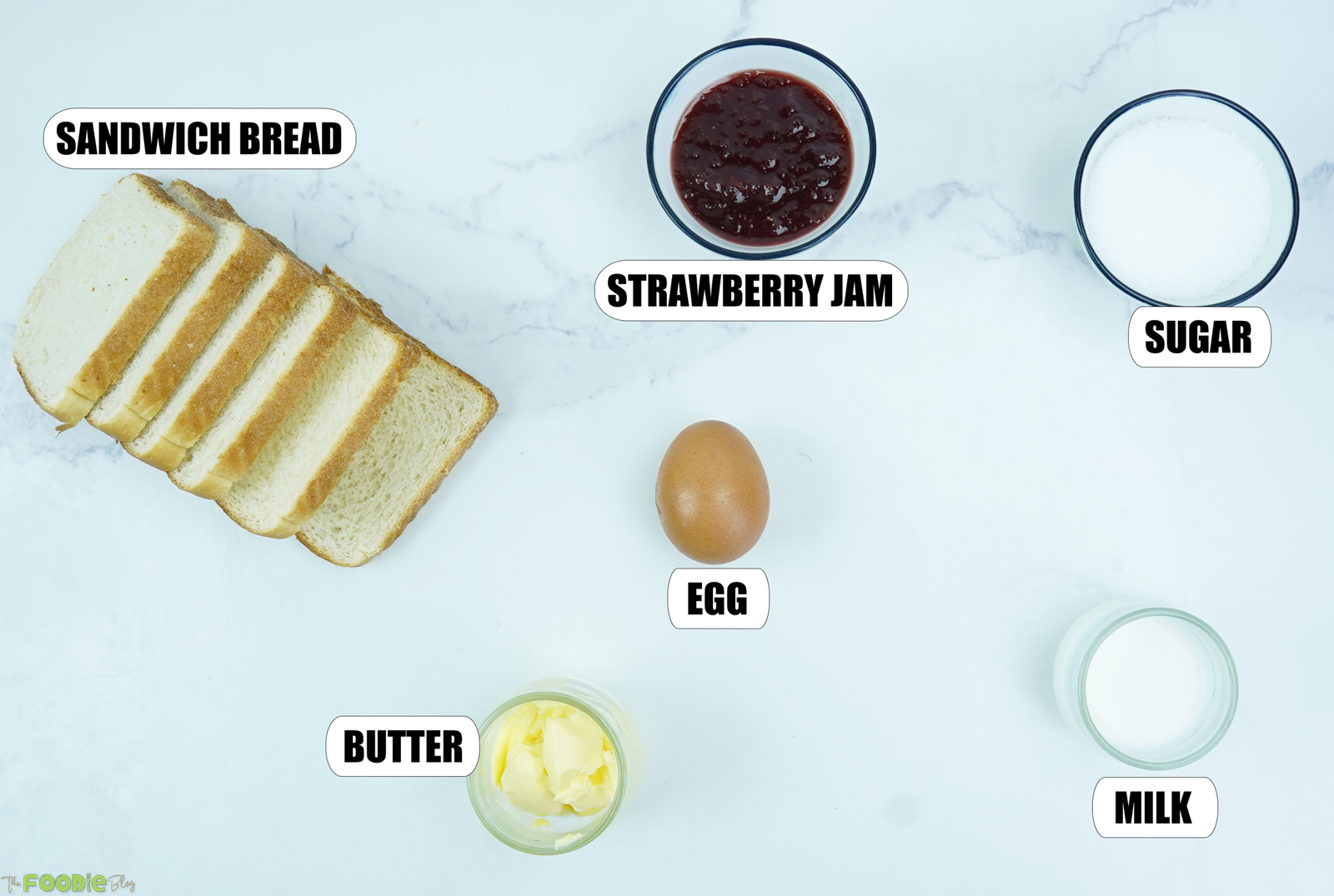White sandwich bread, strawberry jam, sugar, egg, milk, and butter arranged for jam jelly doughnut French toast.