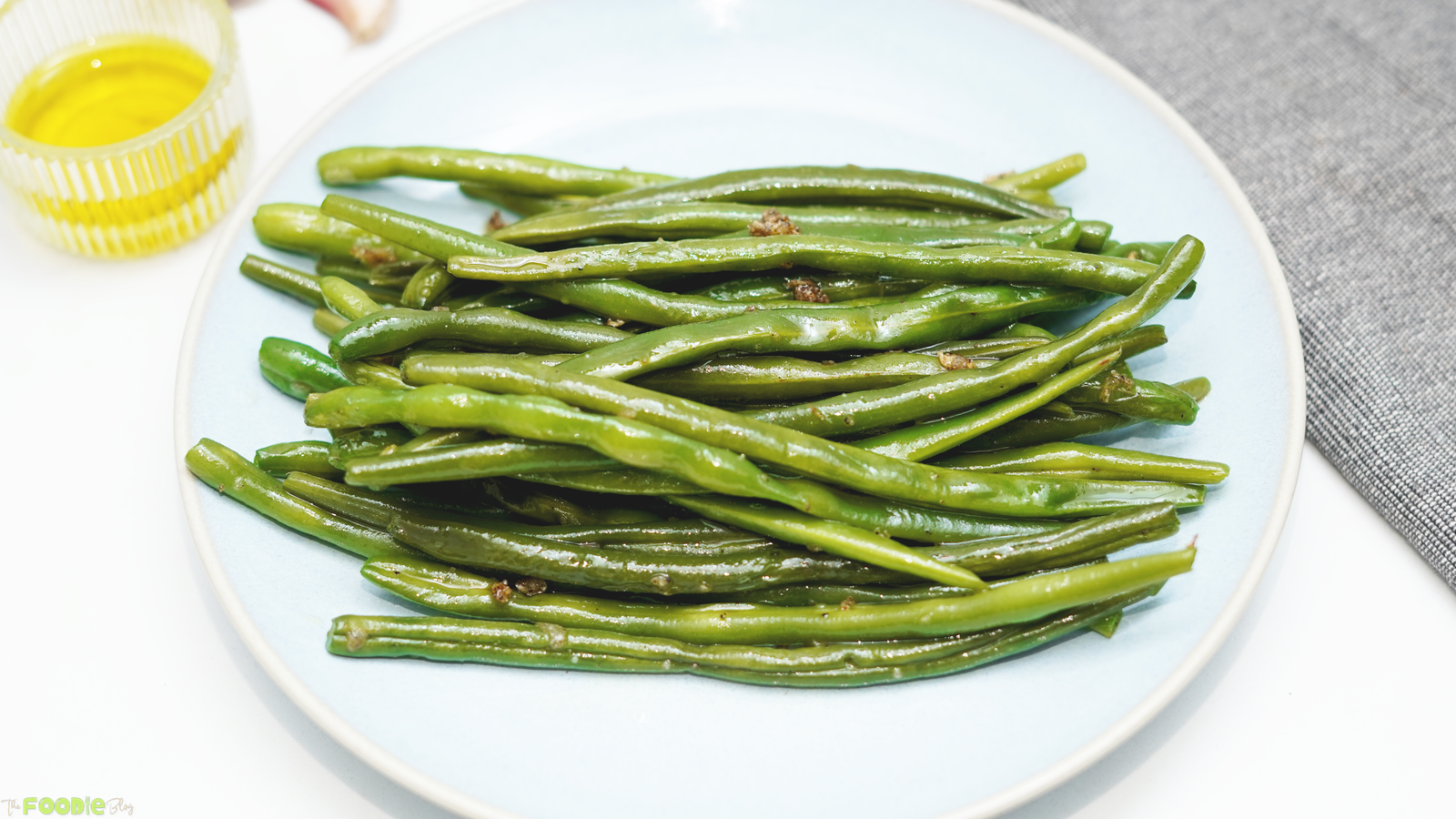 A plate of sautéed green beans with garlic, olive oil, and black pepper.