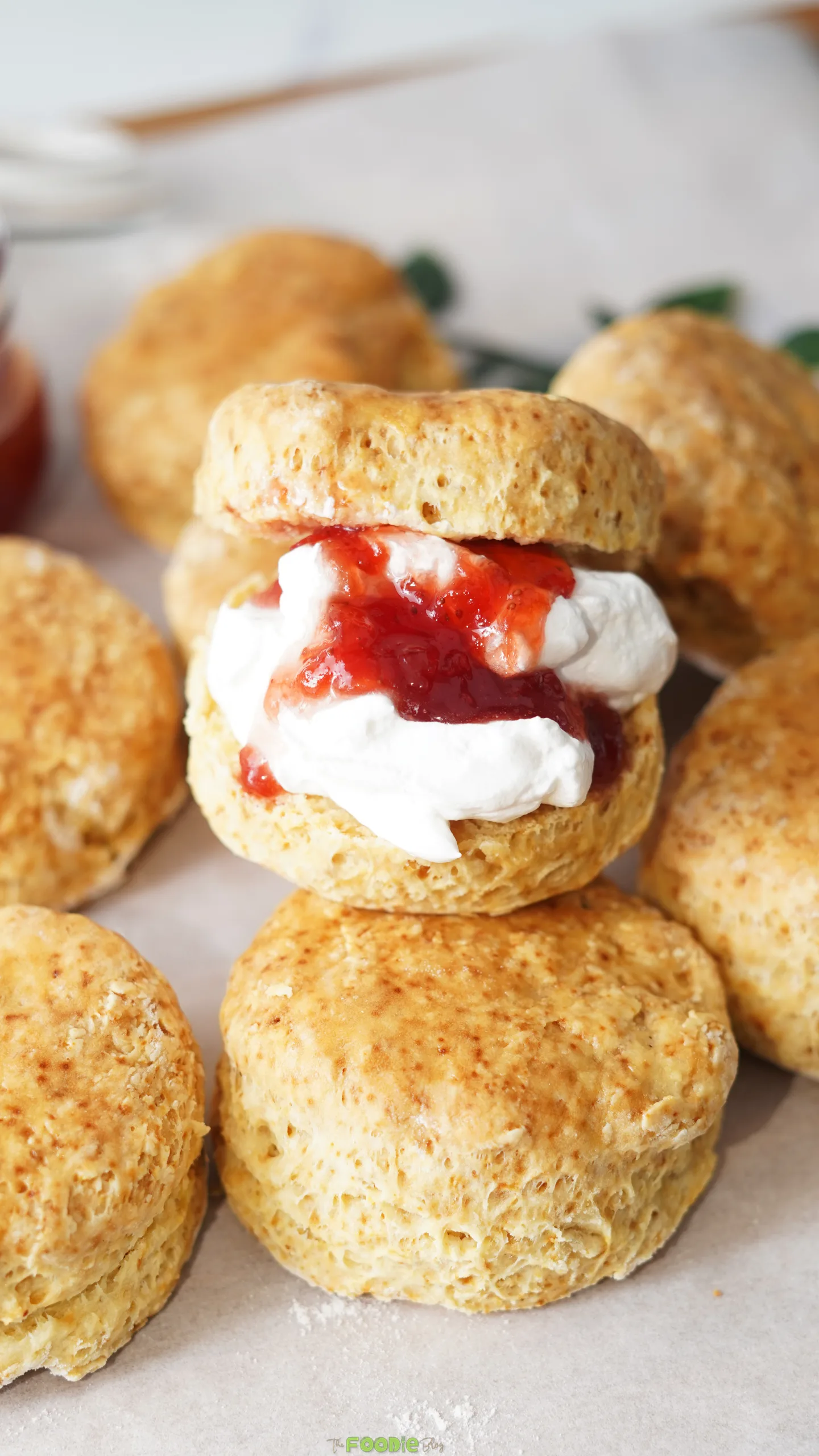 Close-up of soft golden scones with a center scone filled with whipped cream and strawberry jam.