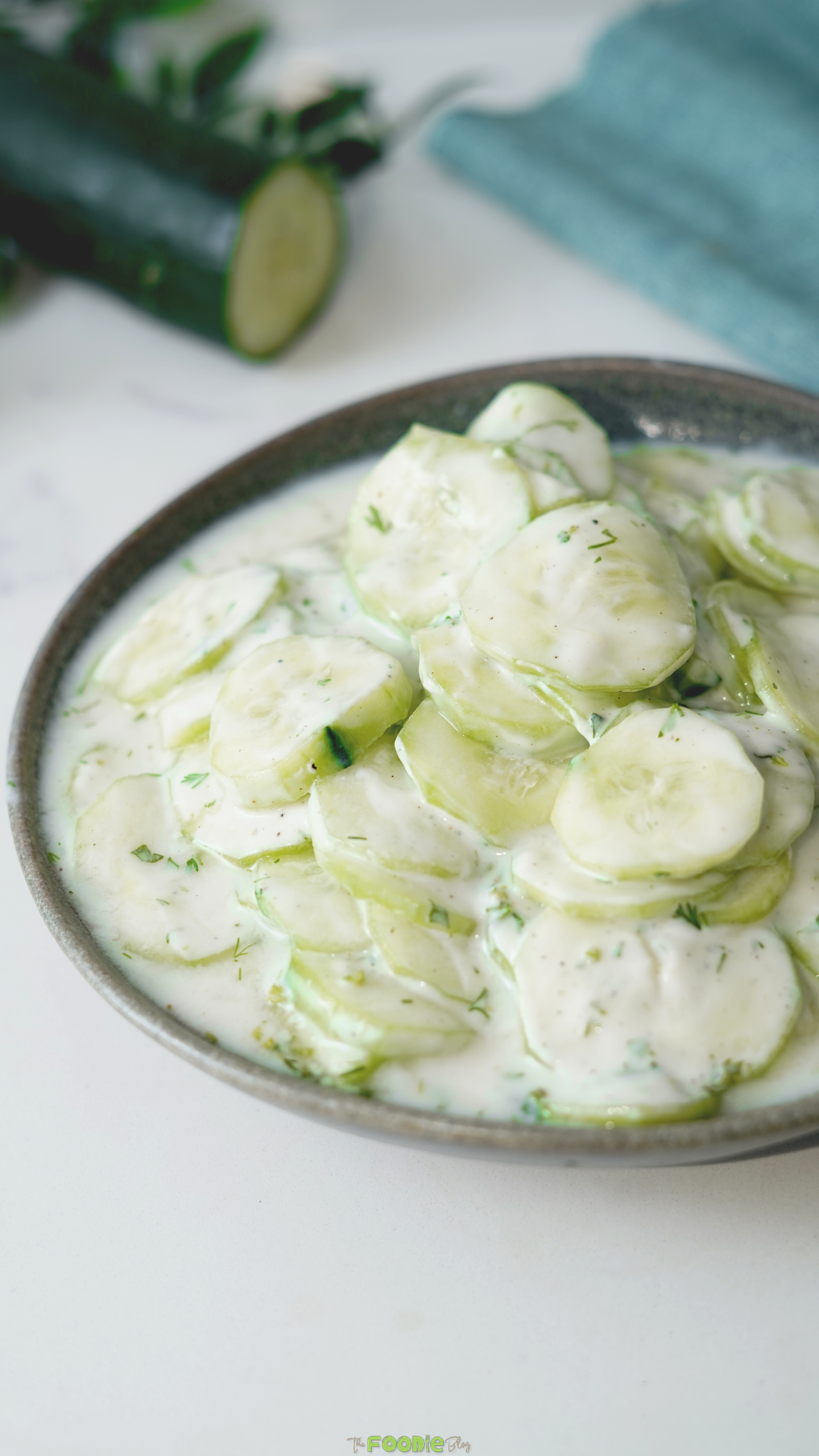 Creamy cucumber salad with fresh dill and thin cucumber slices in a gray bowl