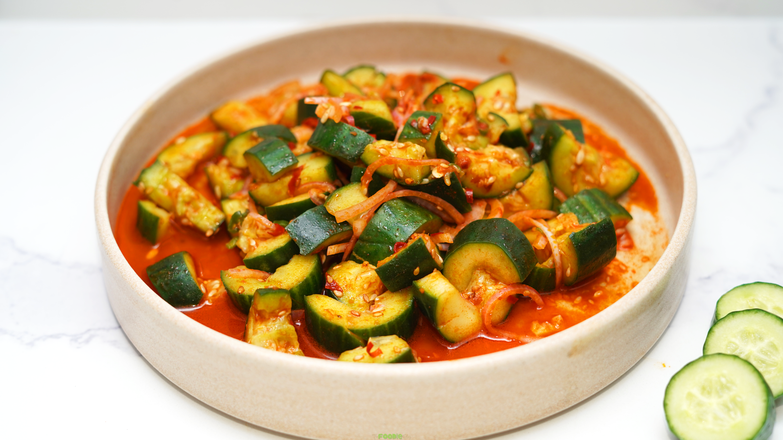 Spicy Asian cucumber salad with smashed cucumbers, red onion, green onions, chili crisp, and sesame seeds.