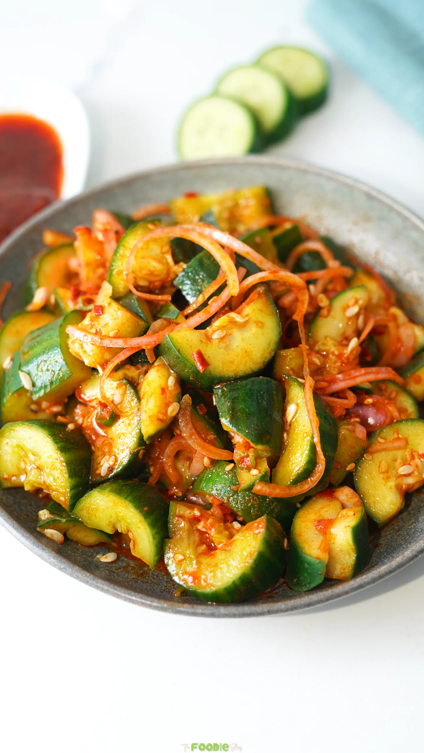 Spicy Asian cucumber salad with smashed cucumbers, chili crisp, red onion, green onions, and toasted sesame seeds.