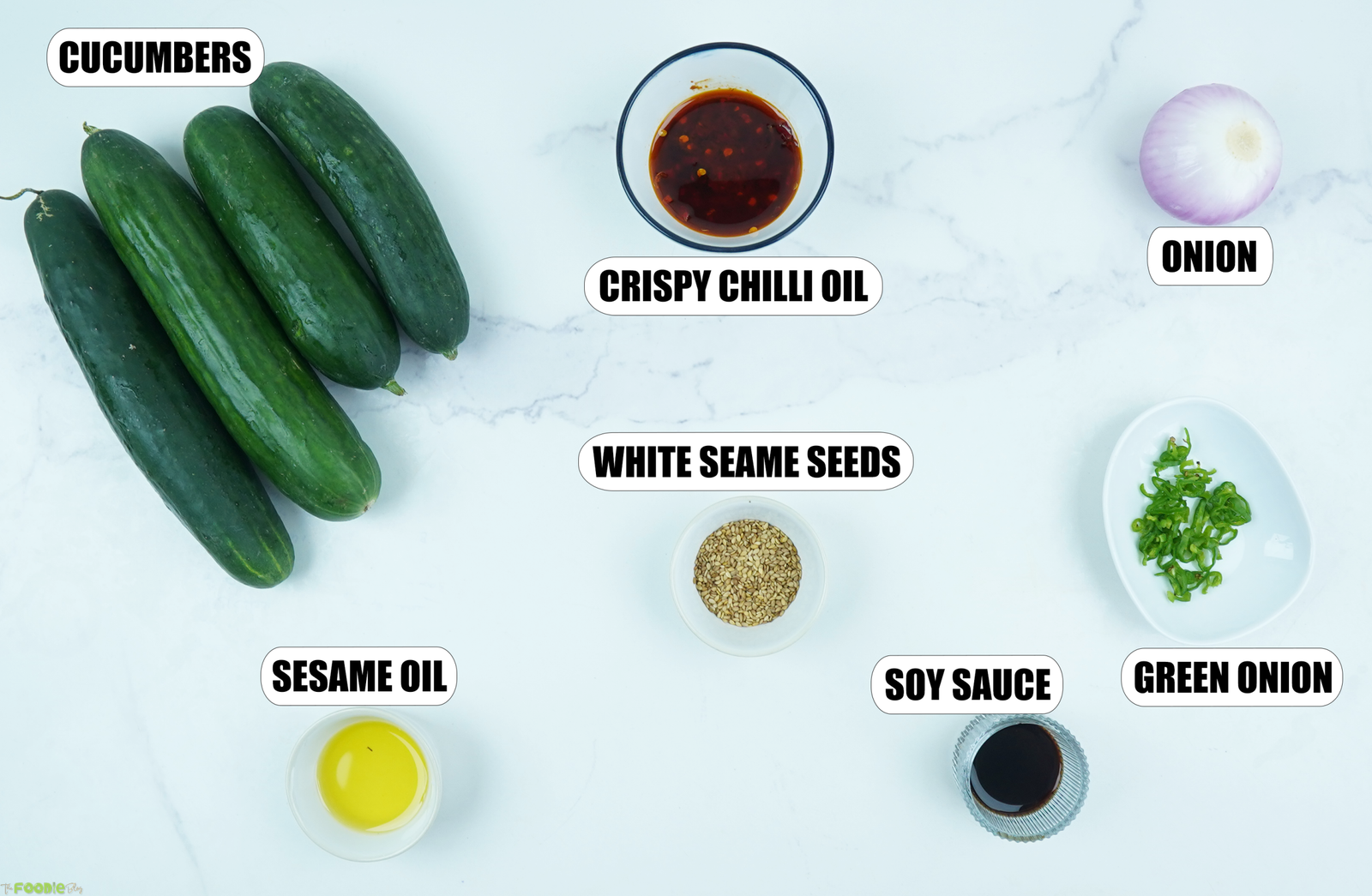 Cucumbers, chili crisp, red onion, green onions, soy sauce, sesame oil, and sesame seeds for spicy Asian cucumber salad.
