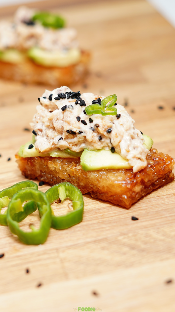 Crispy rice topped with avocado, spicy tuna, green chili slices, scallions, and black sesame seeds