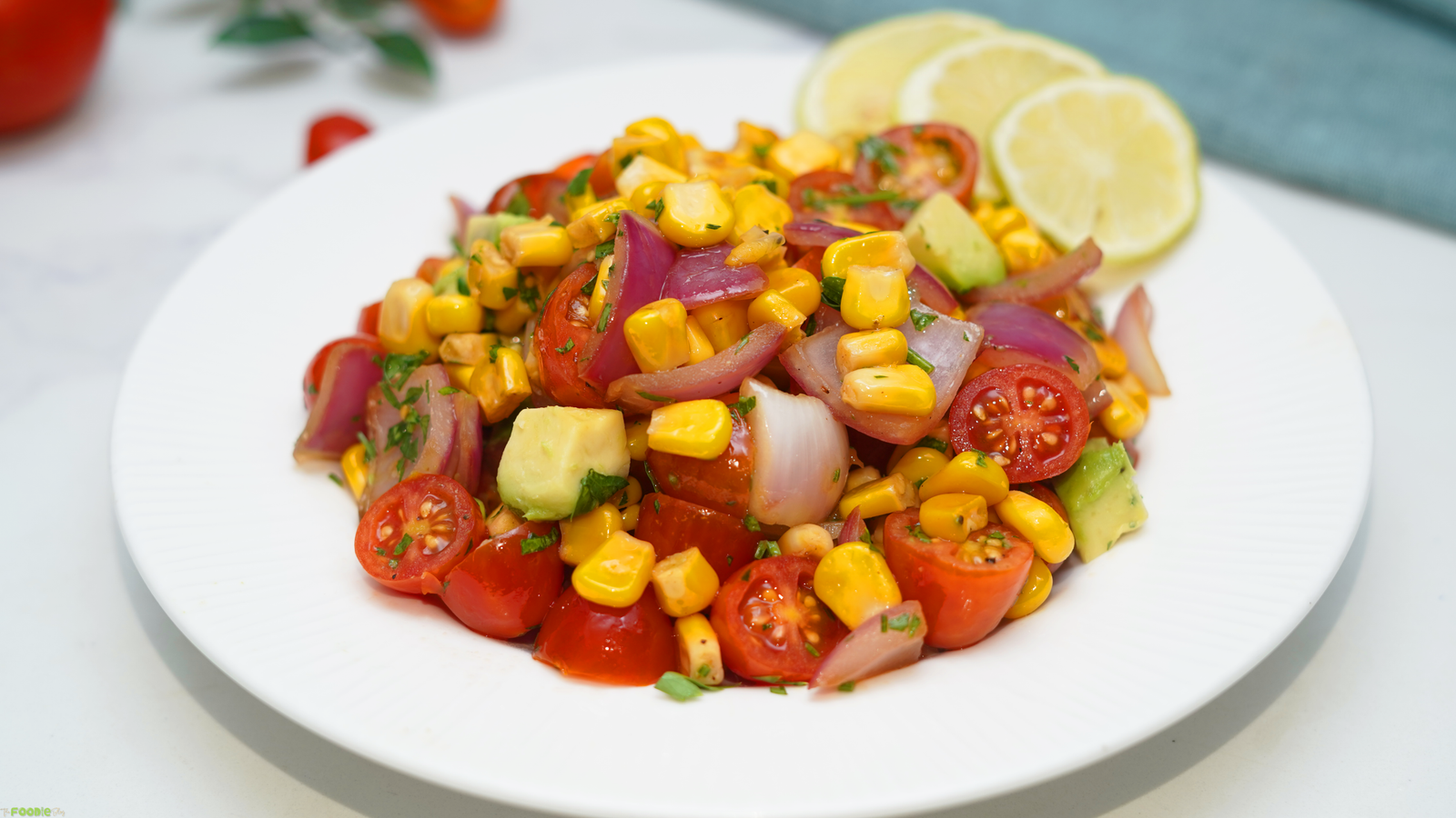 Summer grilled corn and tomato salad with avocado, red onion, parsley, and lime wedges.