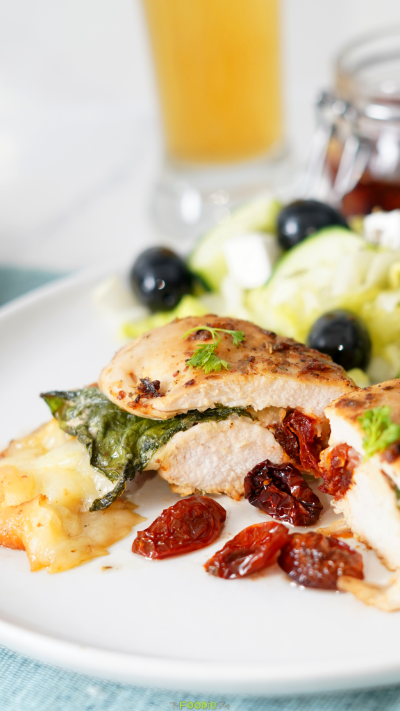 Close-up of sliced stuffed chicken breast showing spinach, melted cheese, and sun-dried tomato filling.