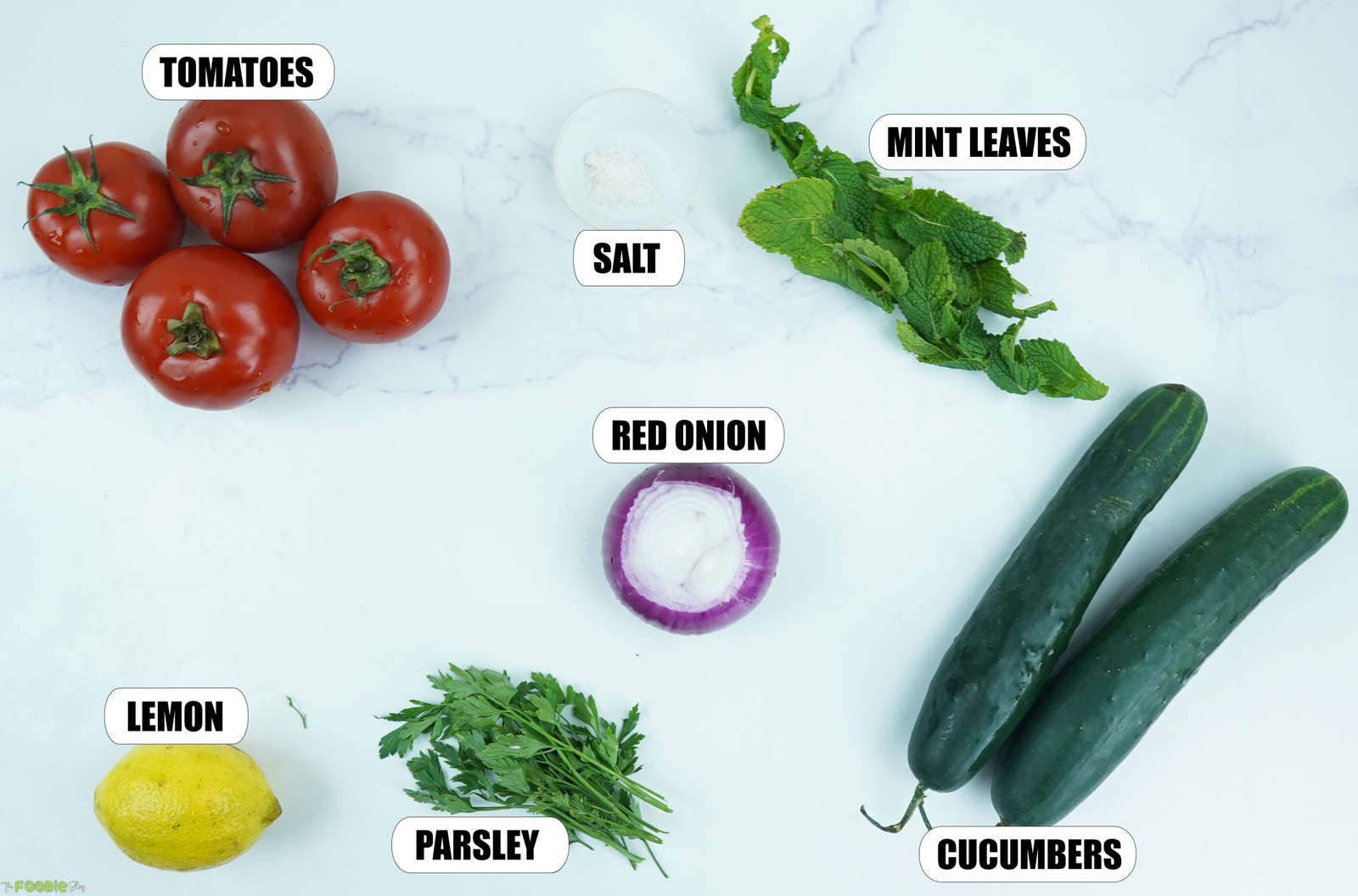 Ingredients for tomato cucumber salad including tomatoes, cucumbers, red onion, lemon, mint, parsley, and salt.