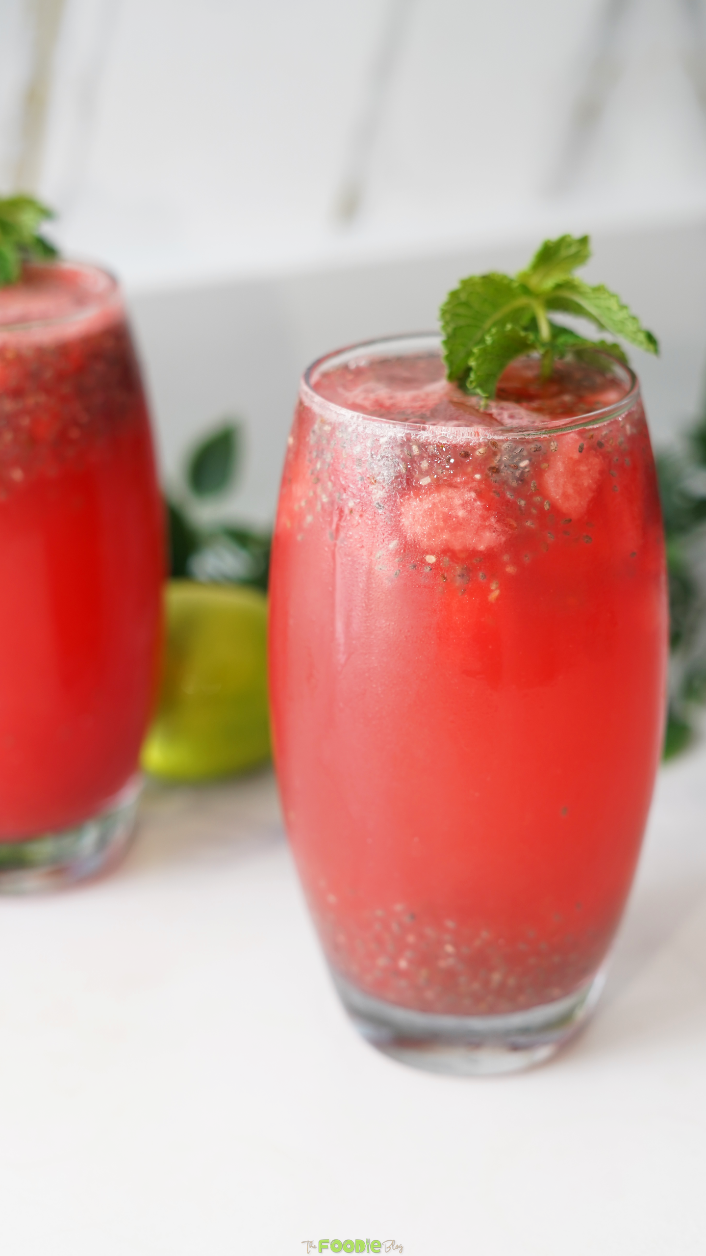 Close-up of watermelon lemonade with mint garnish and basil seeds in a chilled glass.