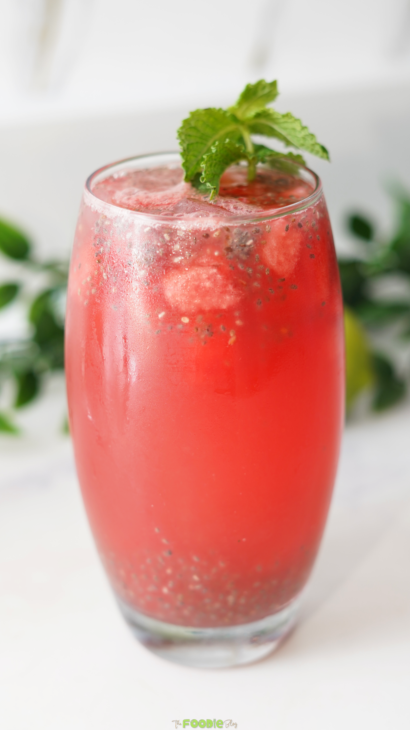 A glass of watermelon lemonade with basil seeds and mint garnish.