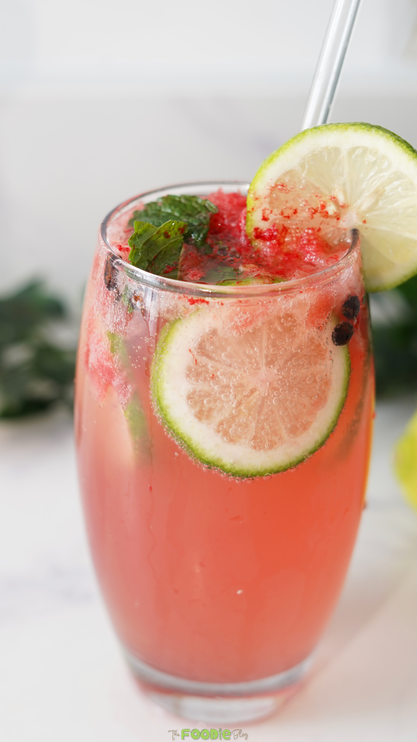 Close-up of a sparkling watermelon mint mojito with lime slices and crushed watermelon.